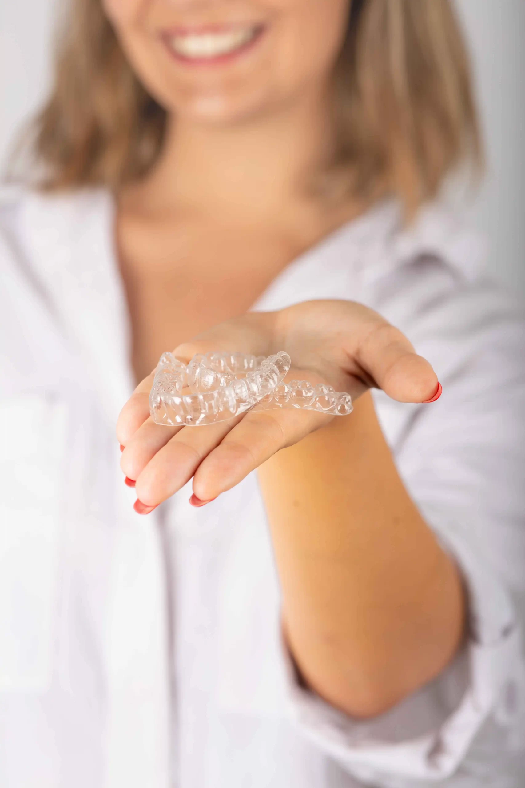 Women showing clear aligners with a confident smile.